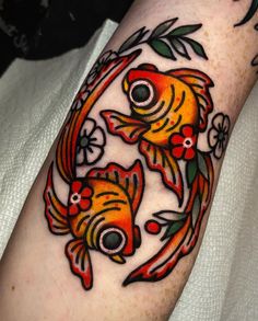 a tattoo with two goldfishs and flowers on it