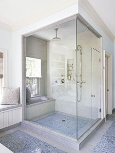 a bathroom with a walk in shower next to a window and rugs on the floor