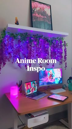 a desk with two computers on it and purple flowers hanging from the ceiling