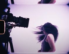 a woman with long hair standing in front of a camera