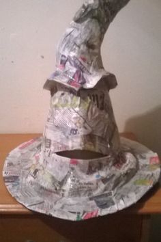 a hat made out of newspaper sitting on top of a wooden table next to a wall