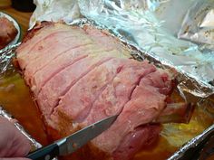 a person cutting meat into pieces on top of tin foil