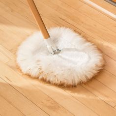 a mop is on top of a wooden floor with a white fuzzy duster