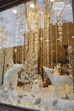 a store window with white christmas decorations and lights hanging from it's windowsill