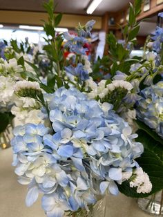 blue and white flowers are in glass vases