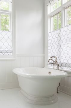 a white bath tub sitting next to two windows