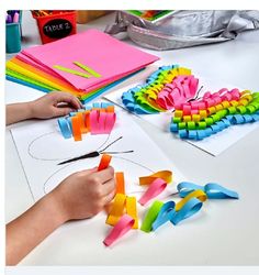 a person is cutting out colored paper with scissors