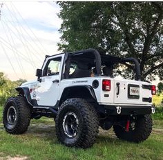 a white jeep parked on top of a lush green field