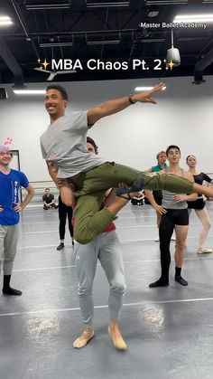 a group of people standing around each other in a dance studio with one man on his back