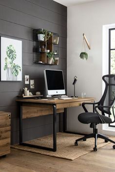 a desk with a computer on top of it in front of a wall mounted planter