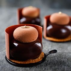 three chocolate desserts are sitting on top of each other with spoons in front of them