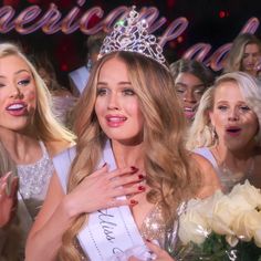 a woman in a tiara is surrounded by other women at a beauty pageant event