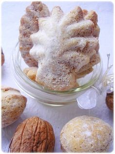 several different types of pastries in a glass bowl on a white tablecloth with almonds