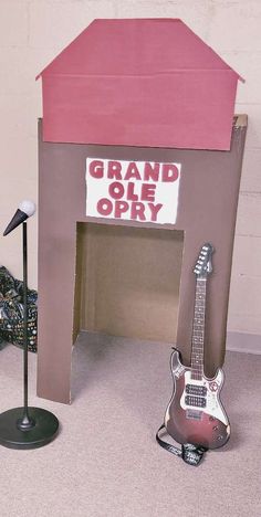 a guitar and microphone stand in front of a grand olee opry sign on the floor