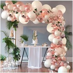 a table topped with lots of white and pink balloons