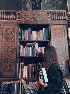 a woman standing in front of a bookshelf filled with lots of book's