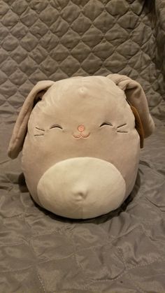 a stuffed animal that is laying down on a bed with it's eyes closed