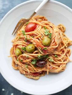 a white bowl filled with pasta and olives