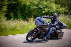 a man riding on the back of a motorcycle down a curvy road with trees in the background