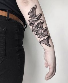 a woman's arm with black ink flowers on the left side of her arm