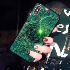 a woman's hand holding an iphone case with a green marble design on it