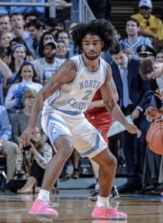 a basketball player dribbles the ball while people watch from the stands watching him