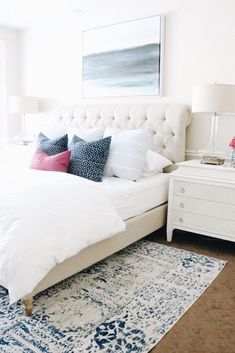 a white bed with blue and pink pillows