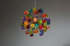 a multicolored glass chandelier hanging from a ceiling in a room with gray walls