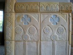 an ornately carved stone fireplace surround in a room with carpeted flooring and windows