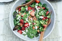 a salad with strawberries and feta cheese in a white bowl on a table