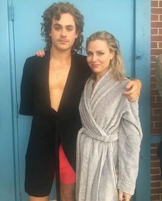 a man and woman standing next to each other in front of a blue wall wearing towels