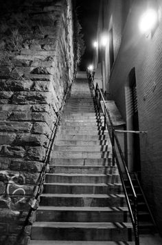 stairs leading up to the top of a stone building at night with lights on them