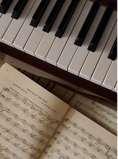 an open book with sheet music on it next to a piano keyboard and piano keys