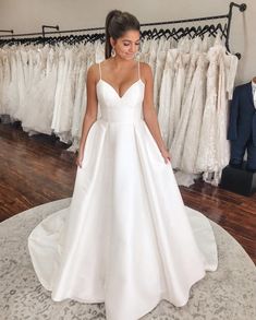 a woman in a white wedding dress standing next to a rack of dresses