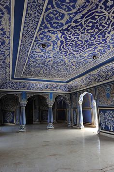 an empty room with blue and white walls, pillars and arches in the center is decorated with intricate designs