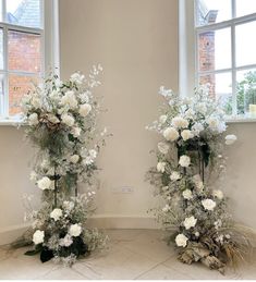 two tall vases with white flowers in them