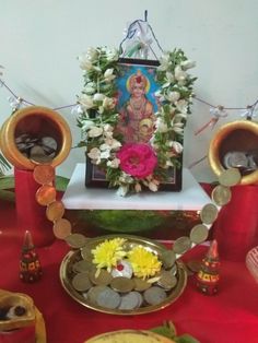 there is a small shrine with flowers and coins in front of it on the table