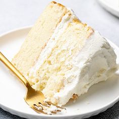 a slice of cake on a white plate with a gold fork in front of it