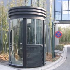 a black round building sitting on the side of a road next to tall bamboo trees