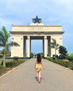 a woman walking in front of an arch with a star on it's top