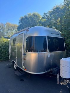 an airstream parked next to some bushes and trees