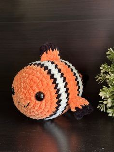 an orange and black striped fish sitting on top of a table next to a potted plant