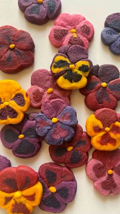 there are many different colored cookies on the table together, including one with yellow and purple flowers