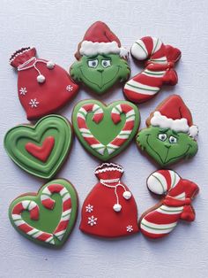 decorated cookies arranged in the shape of heart, elf, and christmas hats on a white surface