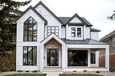 a white house with black trim and windows on the front door is pictured in this image