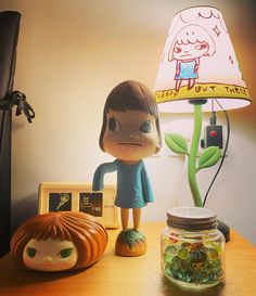 a lamp that is on top of a table next to a figurine and a glass jar