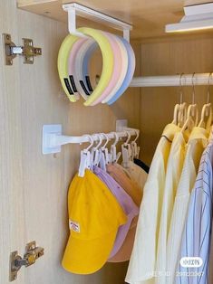 there are many hats and shirts hanging on the hooks in this closet, but no one is looking at them