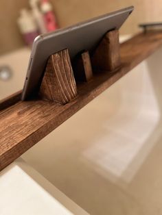 a tablet sitting on top of a wooden shelf in a bath room next to a sink