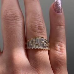 a woman's hand with a gold ring on it and a pink glittery manicure