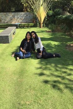 two women sitting on the grass posing for a photo